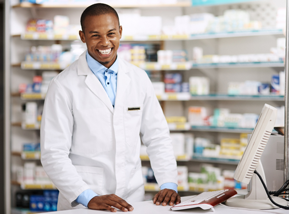 Male-pharmacist-standing-at-a-counter-and-smiling-at-a-hospice-pharmacy-in-Santa-Clarita