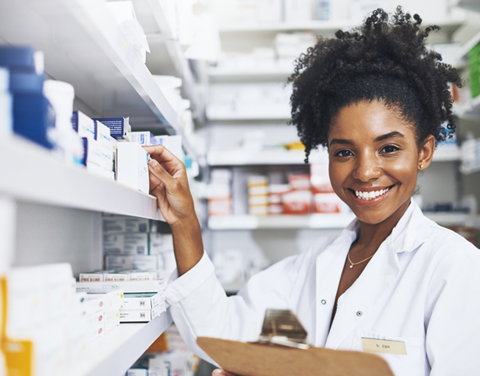 Smiling-female-pharmacist-holding-a-clipboard-and-touching-a-shelf-at-a-hospice-pharmacy-in-Long-Beach
